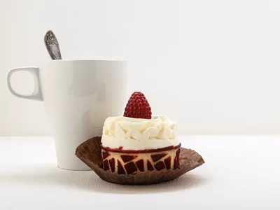 Bolo de caneca low carb de chocolate em caneca branca com cacau polvilhado e colher