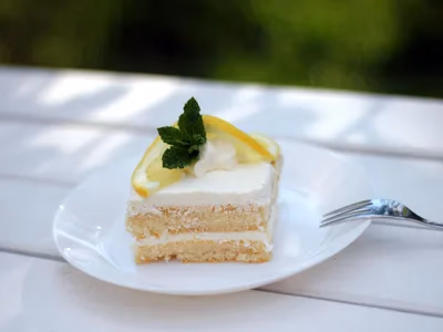 Bolo de limao low carb fatiado em prato branco com raspas de limao por cima