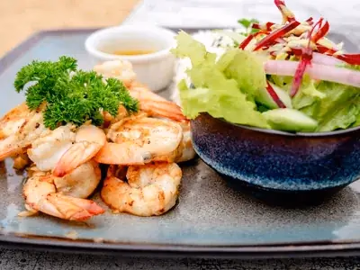 Camarão grelhado dourado sobre salada verde com tomates-cereja