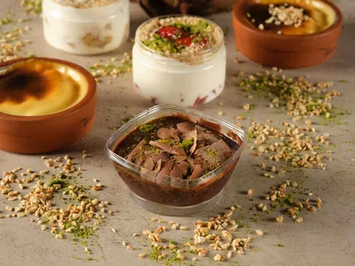 Potinho de danette low carb de chocolate decorado com cacau polvilhado em mesa de madeira