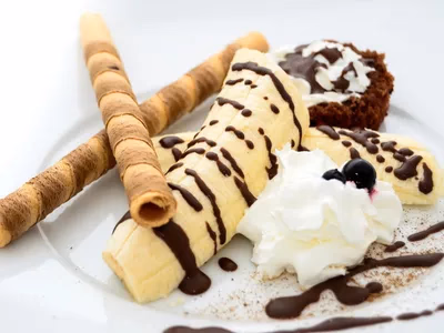 Enroladinhos de banana fit fatiados mostrando o recheio de amendoim e canela em prato branco