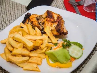 Peito de frango grelhado com marcas de grelha ao lado de legumes coloridos no vapor