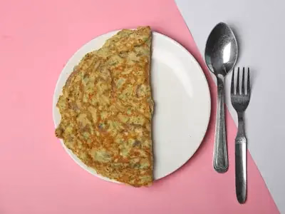 Omelete de claras dourada com espinafre e tomate em frigideira