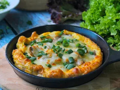 Omelete dourada aberta mostrando recheio colorido de legumes e queijo
