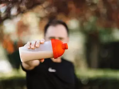 Shake proteico de chocolate cremoso em copo alto com cacau polvilhado
