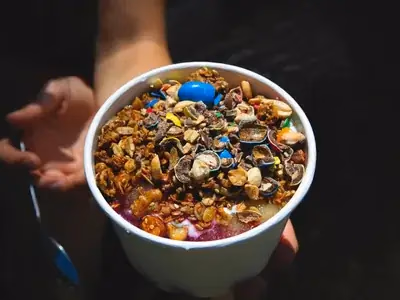 Bowl de açaí roxo escuro decorado com frutas frescas e granola crocante