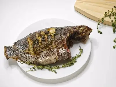 Filé de tilápia dourado assado com ervas verdes e fatias de limão
