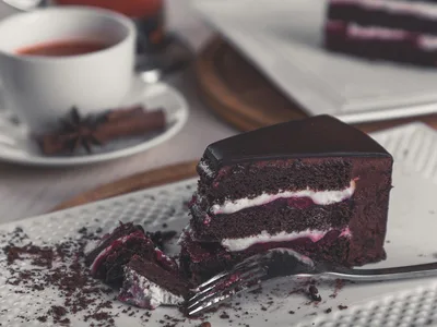 Fatia de bolo de chocolate low carb em prato branco com cacau polvilhado