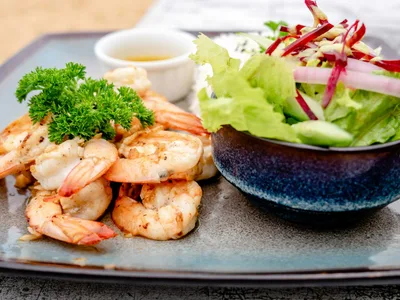 Camarão grelhado dourado sobre salada verde com tomates-cereja