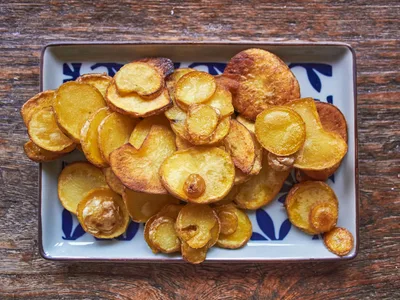 Chips crocantes de batata-doce em laranja vivo sobre papel manteiga