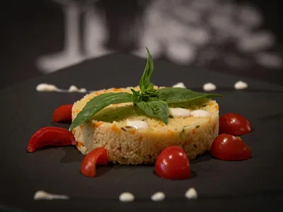 Cuscuz fit de aveia desenformado em prato com queijo cottage e ervas por cima