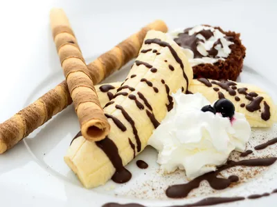 Enroladinhos de banana fit fatiados mostrando o recheio de amendoim e canela em prato branco