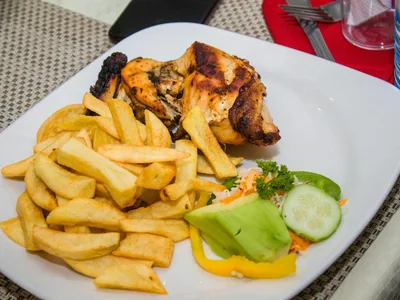 Peito de frango grelhado com marcas de grelha ao lado de legumes coloridos no vapor