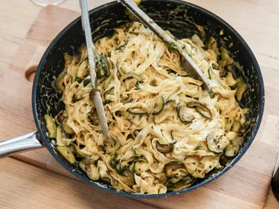 Espaguete de abobrinha com molho branco cremoso e parmesao ralado em prato fundo