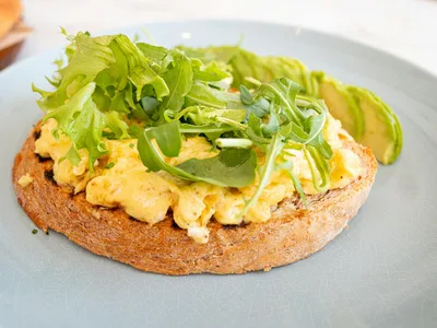 Ovos mexidos cremosos ao lado de fatias verdes de abacate no prato