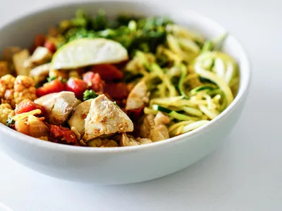 Frango grelhado fatiado ao lado de brocolis salteado no azeite em prato branco