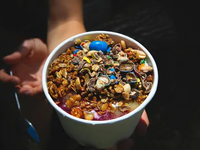 Bowl de açaí roxo escuro decorado com frutas frescas e granola crocante