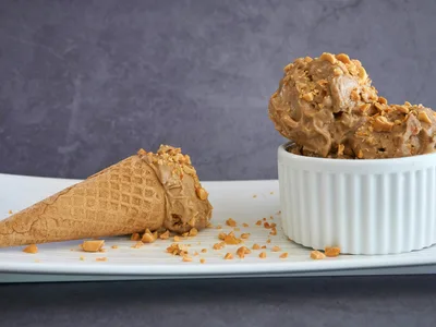 Sorvete cremoso de banana com fio de pasta de amendoim em copo