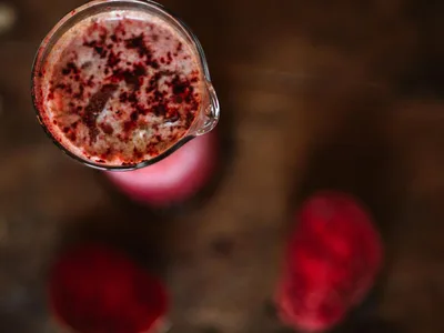 Suco de beterraba vermelho intenso em copo com gengibre ao lado