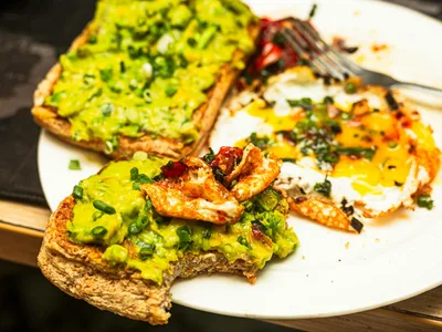 Torrada integral com abacate e ovos mexidos em tábua de madeira